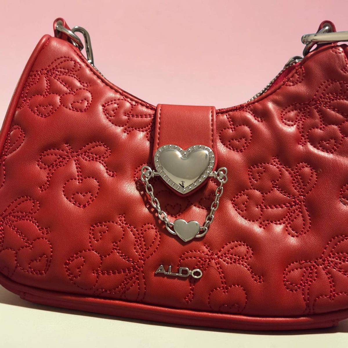 Blanca Closet Aldo red purse with quilted cherry embroidery, silver heart charm, and chain detail on a pink background