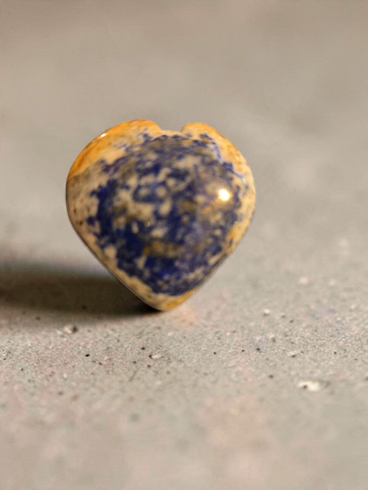 Blanca Closet polished stone heart ornament with blue and tan organic patterns on a textured grey surface